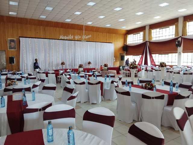 Hall set up with white chair covers and red table runners