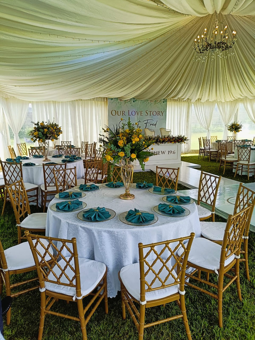 Tent interior with draped ceiling, round tables and Chiavari chairs